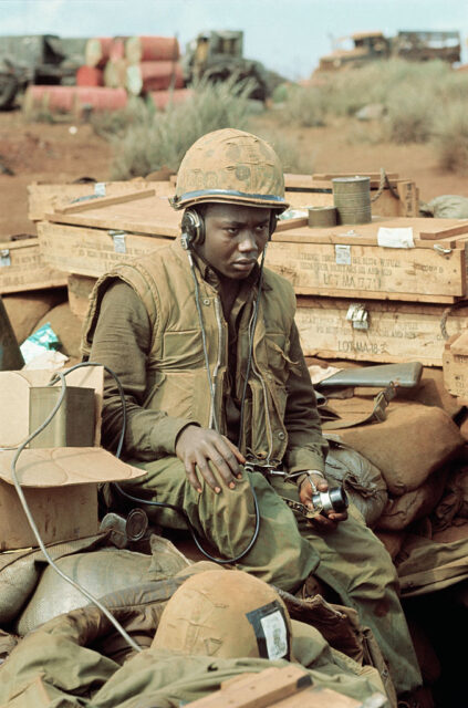 US Marine sitting on boxes while listening to a portable radio
