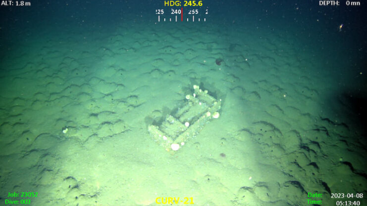 Munitions box covered in sand on the seafloor