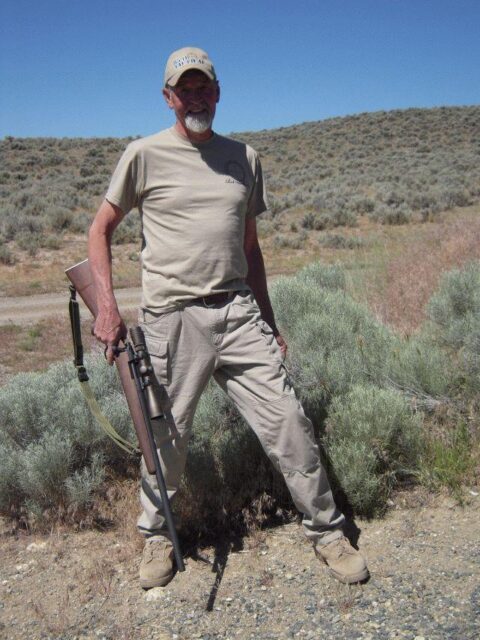 Chuck Mawhinney standing in the desert with a rifle