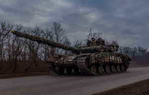 Ukrainian troops driving a military tank down a road