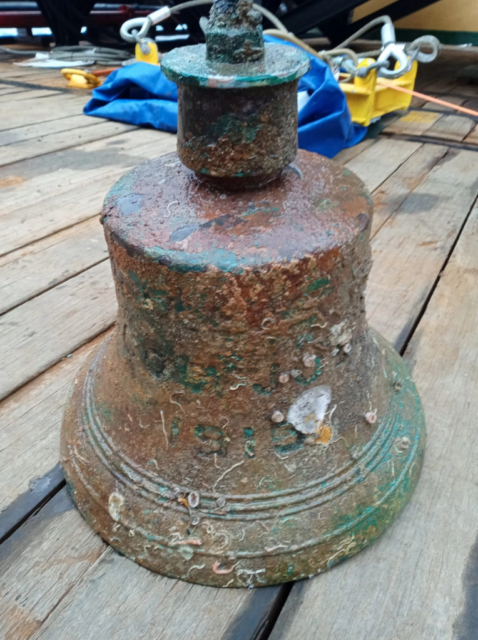 Rusty ship bell placed on a wooden deck