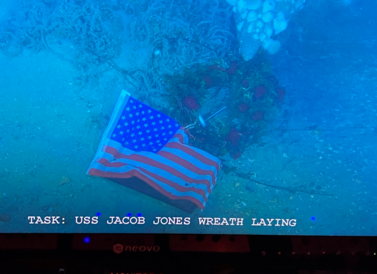 American flag and wreath leaning against the wreck of the USS Jacob Jones (DD-61) on the seafloor