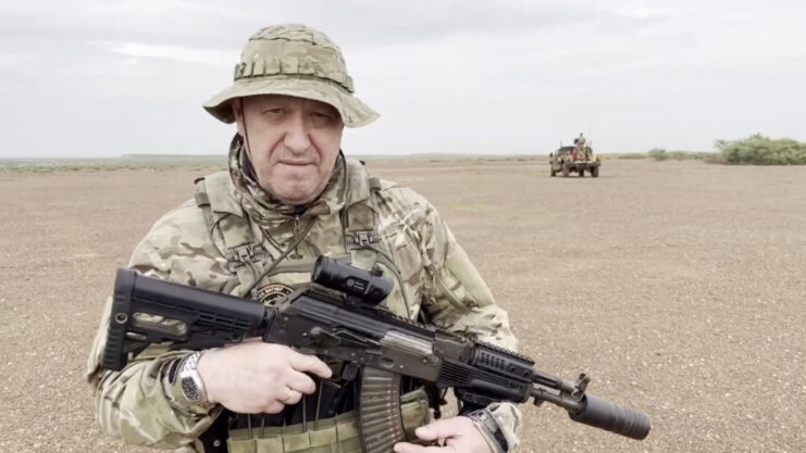 Yevgeny Prigozhin holding a rifle while standing in the desert