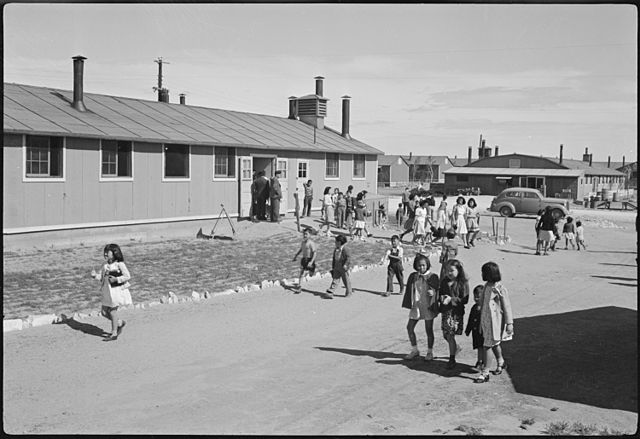 Japanese-American children running past a building at the Granada Relocation Center