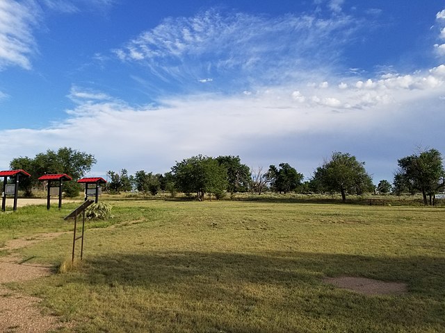 Grassy field at the entrance of the Granada Relocation Center with signs located toward the side