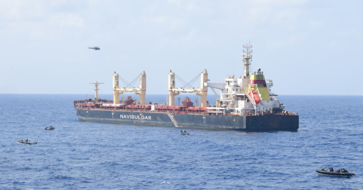 Helicopter hovering over the MV Ruen, while assault boats float near the bulk carrier
