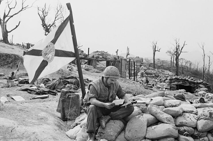 Sgt. Joseph Michael Jones reading a letter while sitting atop sandbags