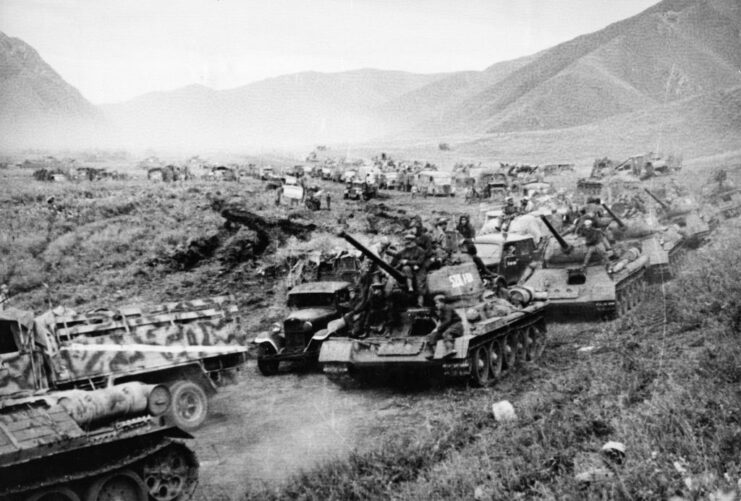 Soviet military tanks driving single-file through a valley