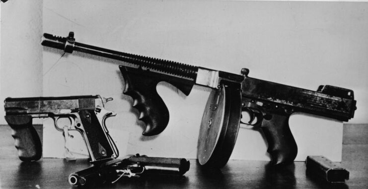 Tommy Gun and two Colt .45 pistols placed on a wooden table