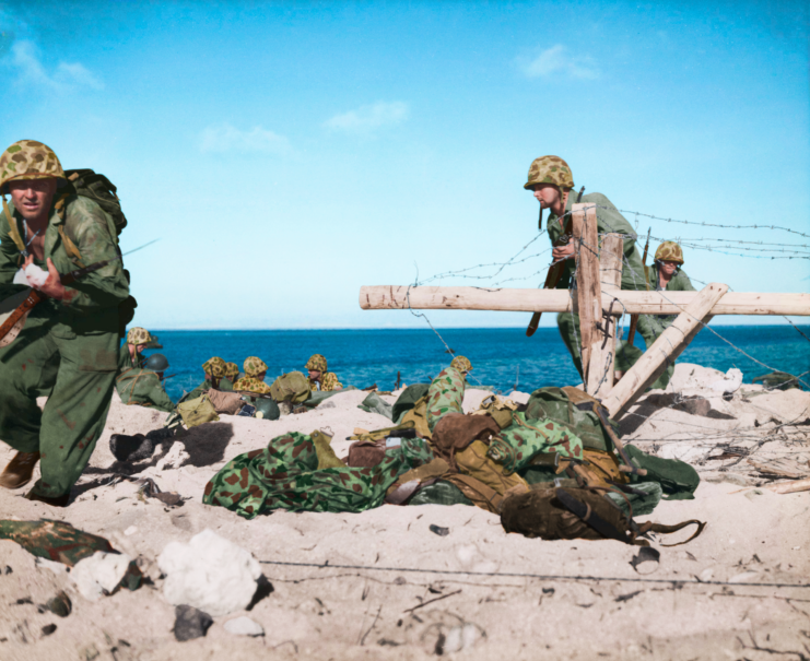 US Marines running past abandoned uniforms and gear on the beach on Betio island