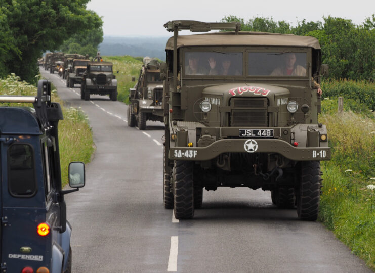 World War II-era vehicles driving down a country road