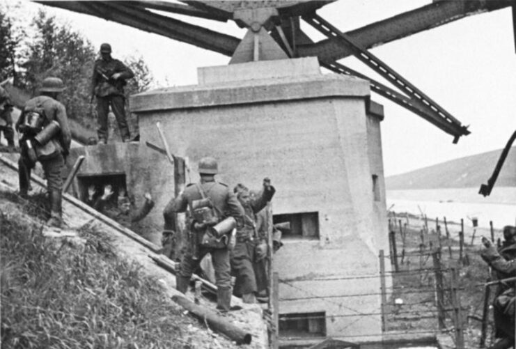Belgian soldiers surrendering to German troops at the foot of a bridge