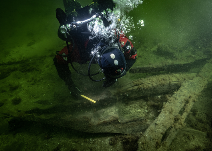 Diver examining a piece of timber on the seafloor