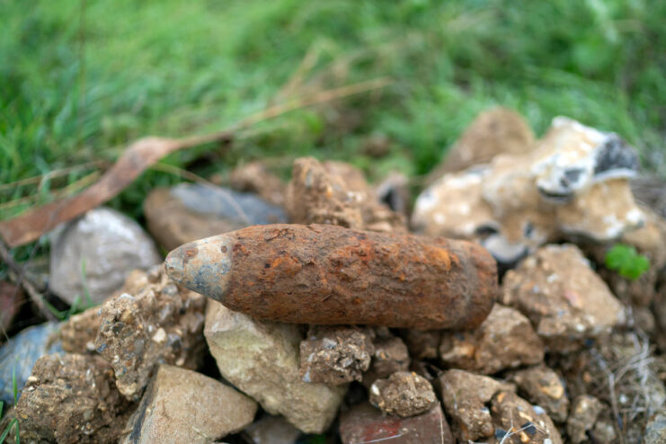 Rusty World War I-era artillery piece balancing atop a pile of rocks
