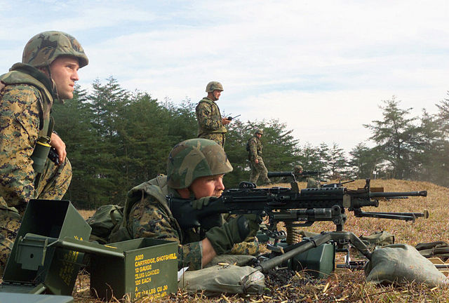 Instructors watching US Marines firing M249 SAW machine guns