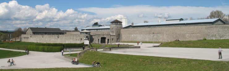 People walking along the exterior wall of Mauthausen concentration camp
