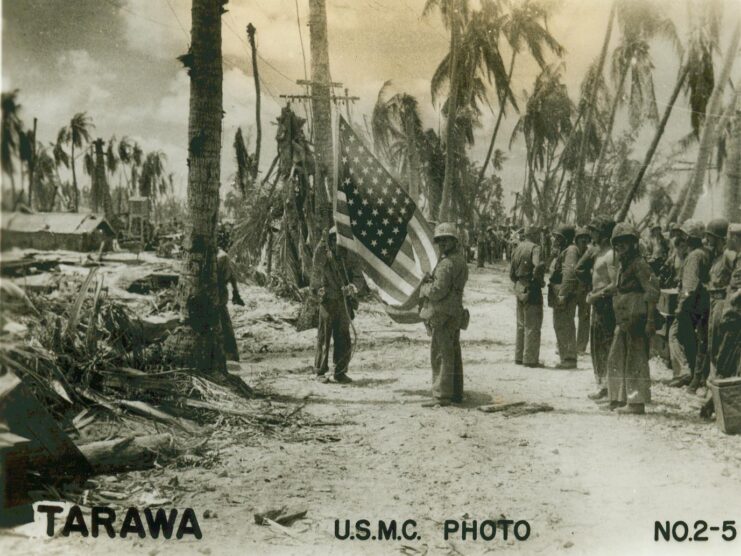 Group of US Marines watching their comrades raise the American flag