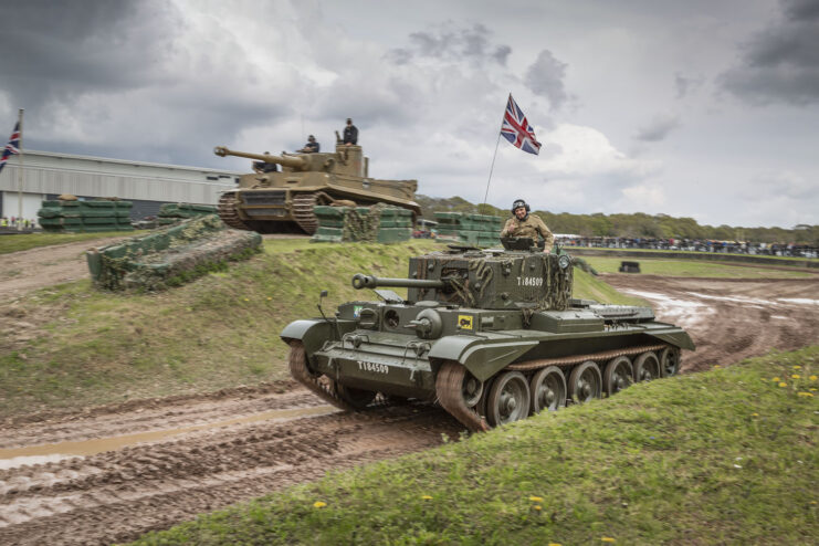 Tiger 131 and a Churchill tank driving along dirt tracks