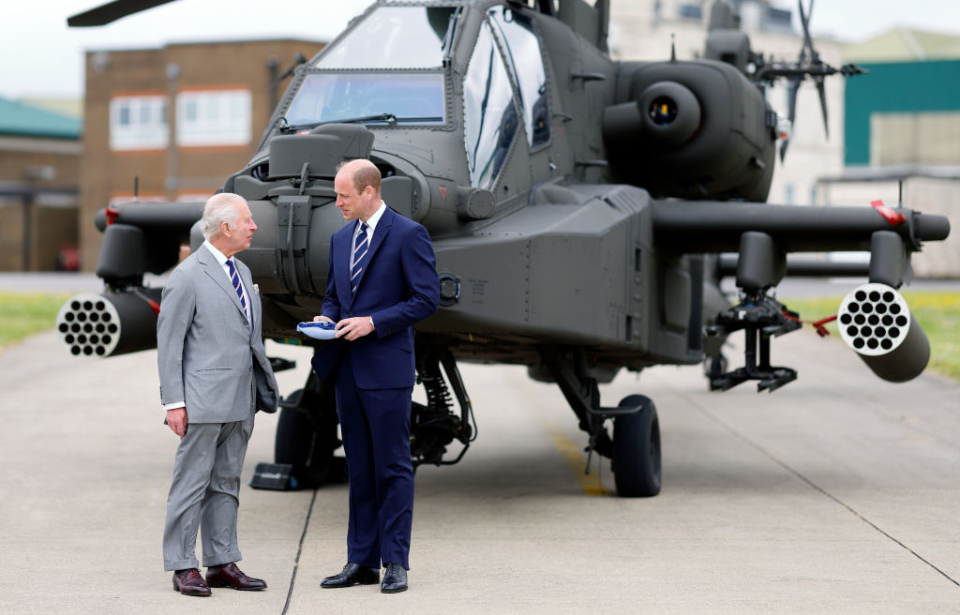 King Charles III and William, Prince of Wales standing in front of a Boeing AH-64 Apache