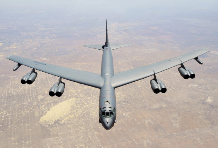 Top-down view of B-52 Stratofortress flying over the ground.