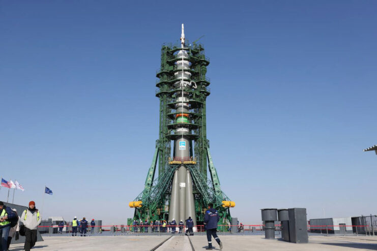 People walking by a platform with a Soyuz MS-25 launch vehicle sat atop it