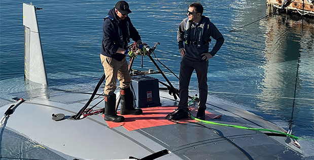 Kyle Woerner and a worker from Northrop Grumman standing atop the Manta Ray UUV while it's in the water