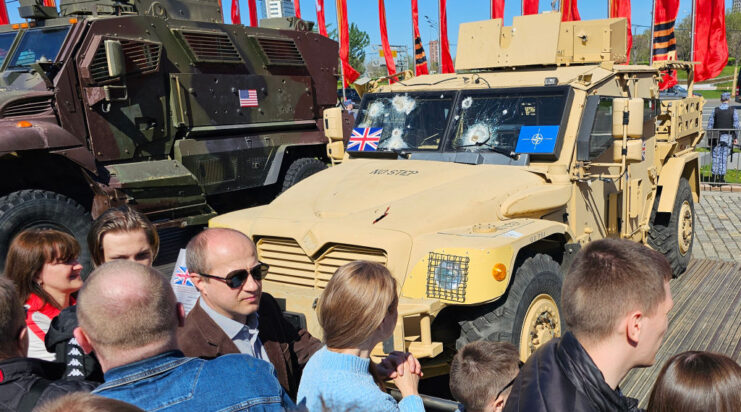 Lines of people walking past military vehicles