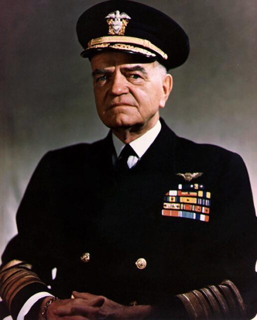 Portrait of man in US Navy uniform in front of grey background.