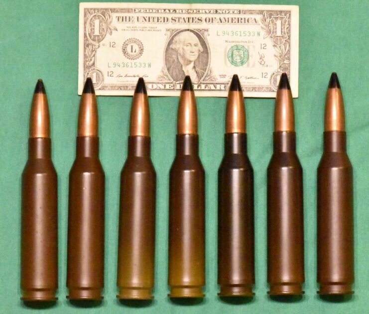 Seven rounds of 14.5 x 114 beside an American dollar bill.