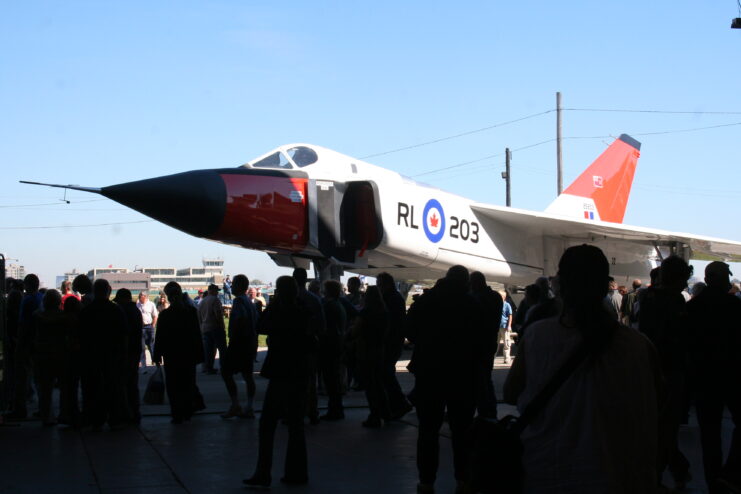 Silhouette of people standing in front of a replica of the Avro Arrow.