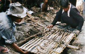 Two Vietnamese guerrillas laying a trap in the ground