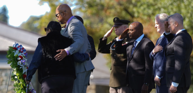 Waverly Woodson's family members and US Army personnel standing before a wreath