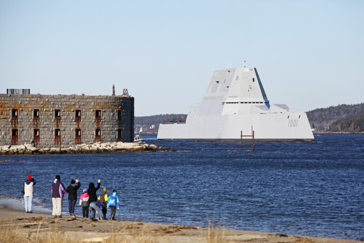 People watching a Zumwalt-class stealth destroyer pass by.