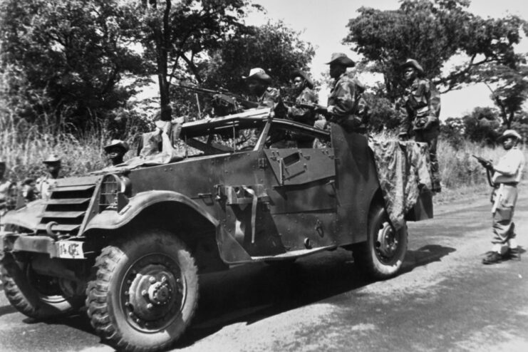 Katangese troops with machine guns standing around a vehicle