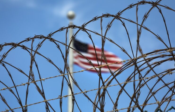 American flag behind razor wire.