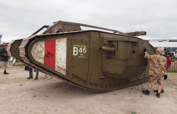 People standing around a World War I-era tank parked outside