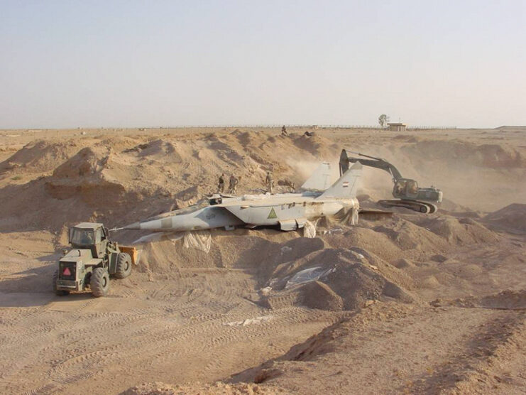 A buried MiG-25R being dug up in the desert.