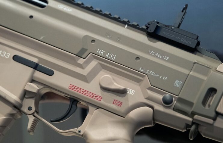 A man holding a HK 433 in his hands.