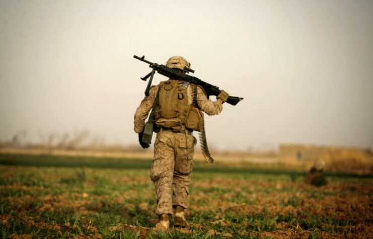 A US Marine with 1/3 Marines Weapons company carries an M240 machine gun over his shoulder during a patrol over farmland in the northeast of Marjah on February 14, 2010.