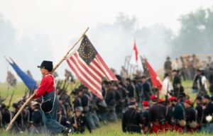 A child reenactor carries a flag during the 160th reenactment of the Battle of Gettysburg, at Daniel Lady Farm in Gettysburg, Pennsylvania, on June 30, 2023.