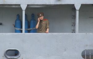 Woman in North Korean military clothes talking on the phone aboard the USS Pueblo.