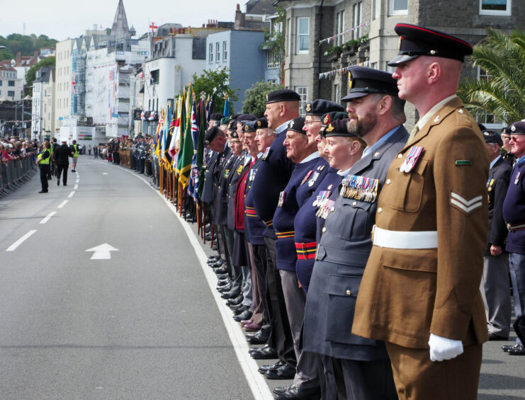 Troops and veterans standing along a road