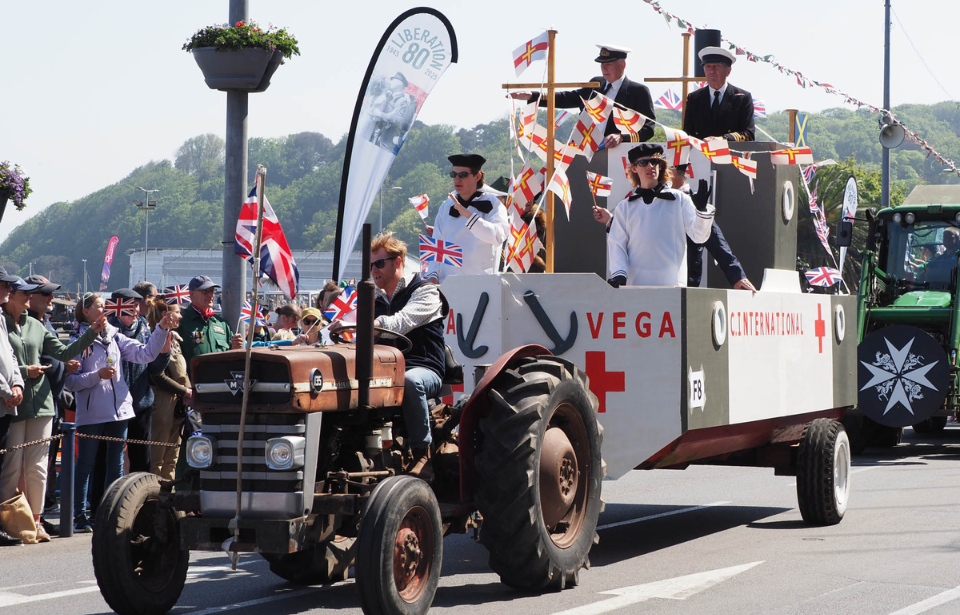 Tractor pulling a trailer designed to look like the SS Vega, with people standing in it