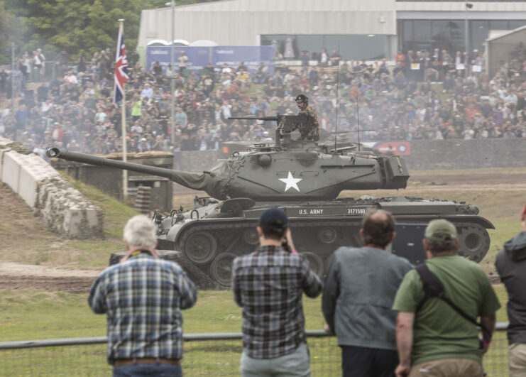 Crowd watching an M47 Patton drive around a dirt track