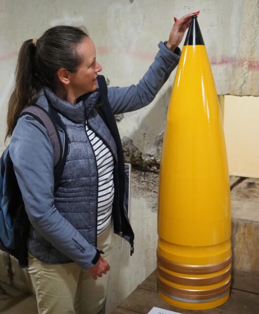 Amanda Johns standing next to an imitation artillery shell