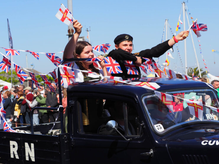 Children standing in the back of a truck, waving Union Jack flags