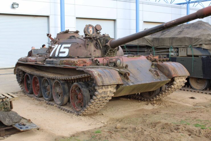 T-55A parked outside of a garage, next to other military vehicles
