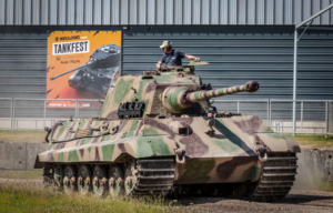 Man standing in a King Tiger that's parked outside of a building