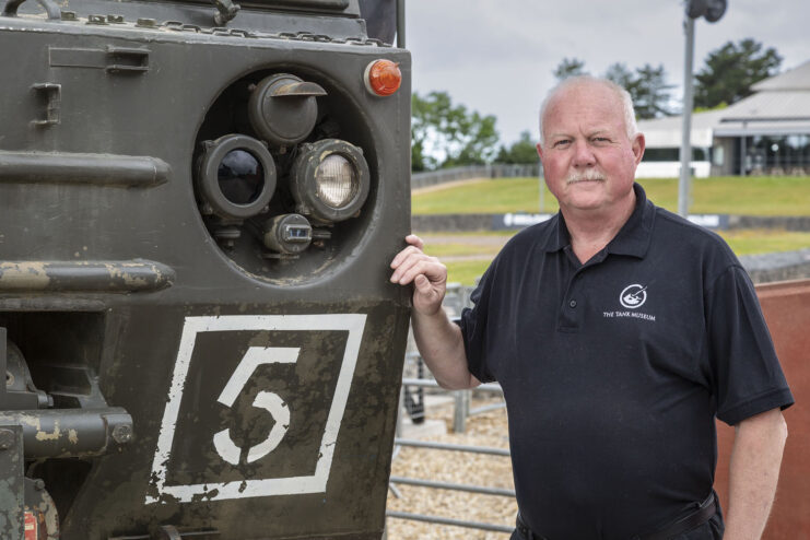 Duncan Masters standing next to a large armored vehicle