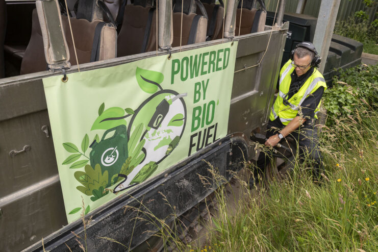 Worker crouched beside a sign that reads, "POWERED BY BIOFUEL"